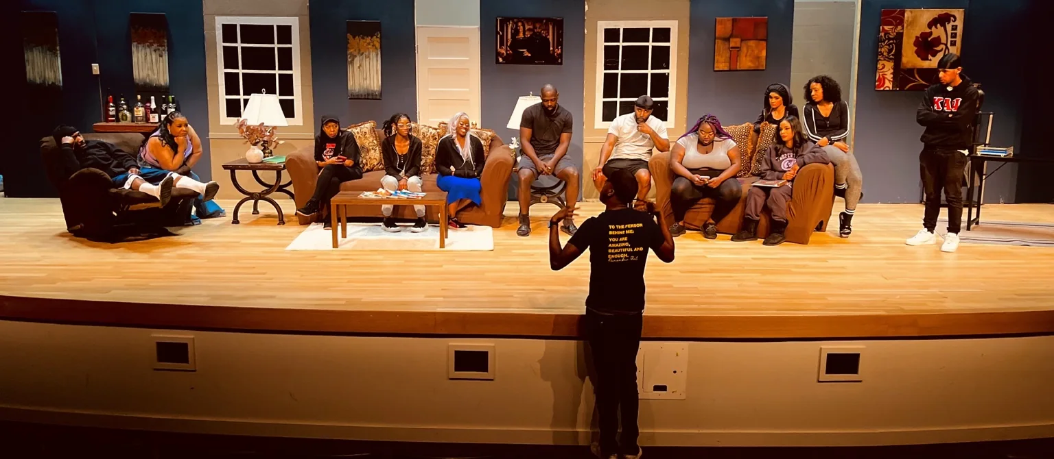 CORTA addressing a cast on a theatre stage